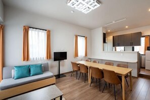 A modern living room with a sofa, TV, and dining area. - KAIGAN HAJIME HUB (Tokyo)