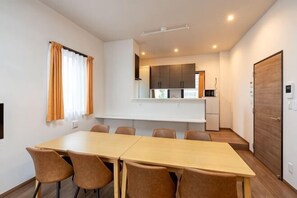 Een moderne hotelkamer met een grote eettafel, een kitchenette en een aparte entree.