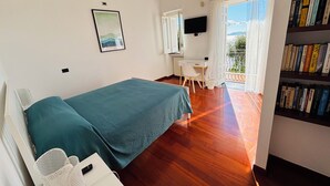 Una camera da letto con un letto, una scrivania, una sedia, una libreria e una finestra con vista.