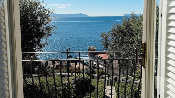 Un balcone con vista sul mare e montagne in lontananza.
