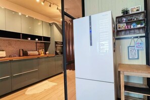 A modern kitchen with a refrigerator, wooden countertop, and cabinets. - Bangi Avenue Charming 4BR Blissful Double Storey (Kajang)