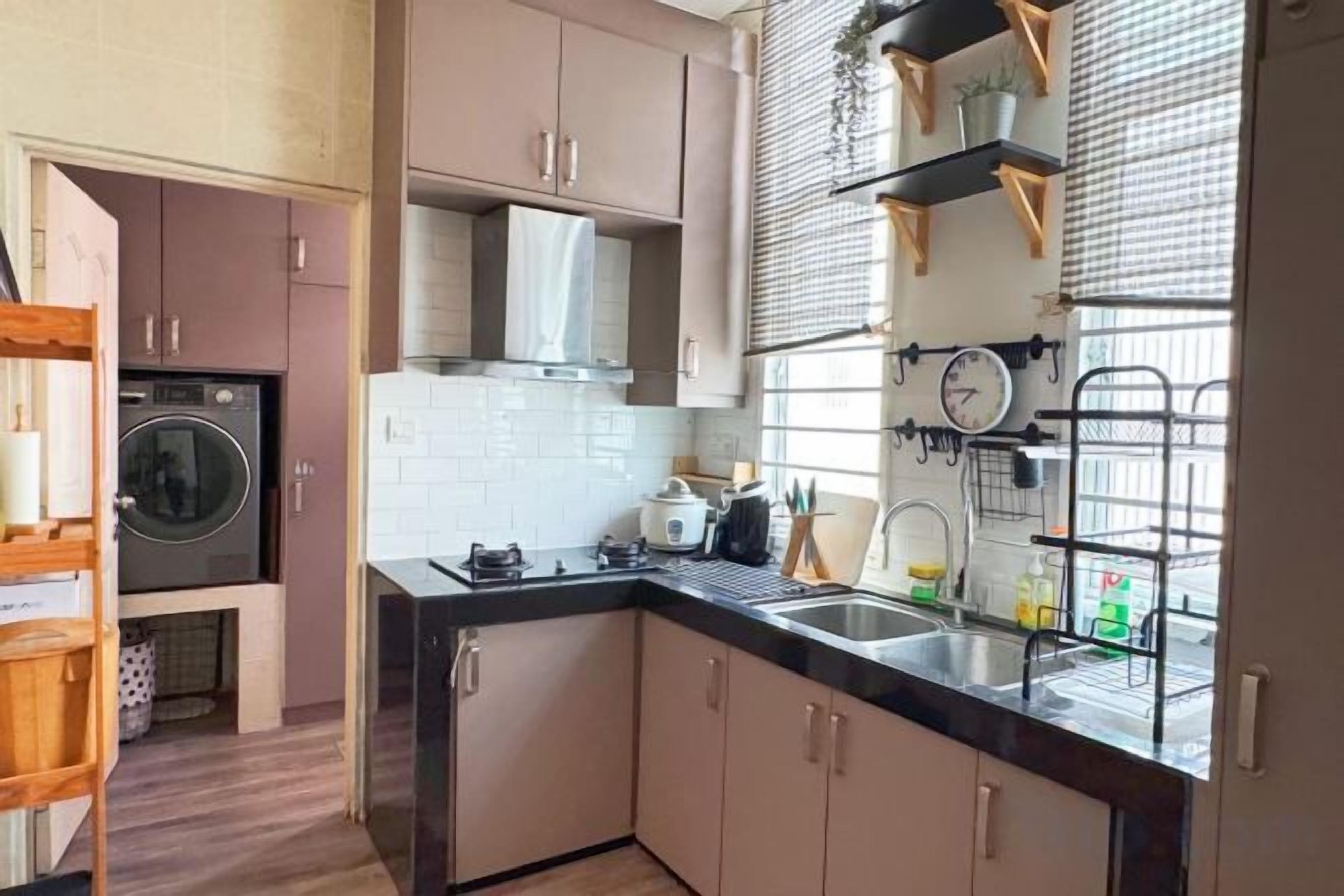 A compact kitchen with a built-in oven, a sink, and a window with blinds.