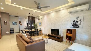 Una sala de estar moderna con un sofá, televisión y zona de comedor.