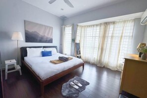 A hotel room with a bed, bedside table, lamp, and a view of the outside through large windows. - Bangi Avenue Charming 4BR Blissful Double Storey (Kajang)