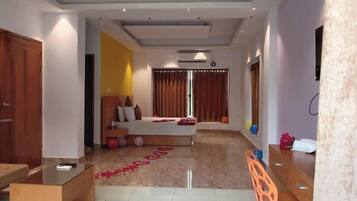 A modern hotel room with a bed, a desk, and a chair. There is a window with curtains and a ceiling fan.