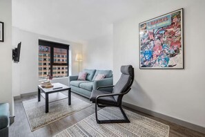 A living room with a sofa, a chair, a coffee table, a rug, a lamp, and a large poster on the wall. - Host & Stay The Roscoe Nest (Liverpool)