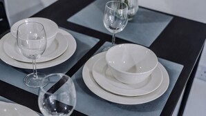 Ein Tisch ist mit weißen Tellern, Schüsseln und Weingläsern gedeckt.