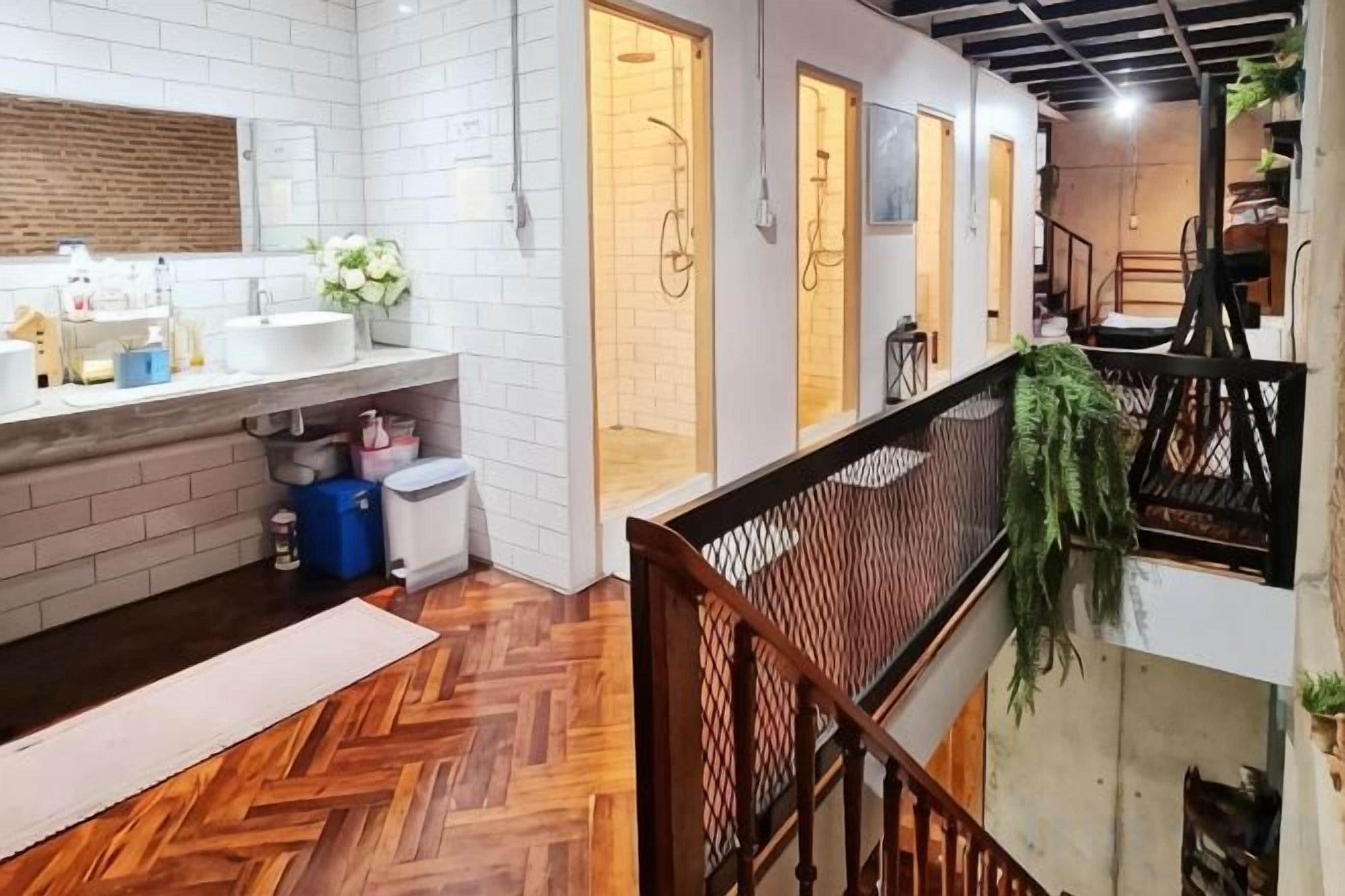 A hotel bathroom with a large mirror, white tiles, and a wooden floor.
