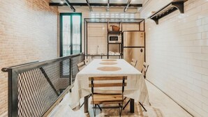 A narrow hallway with a table and chairs, a metal railing, and a brick wall. - MEEMAW'S HOUSE (Bangkok)