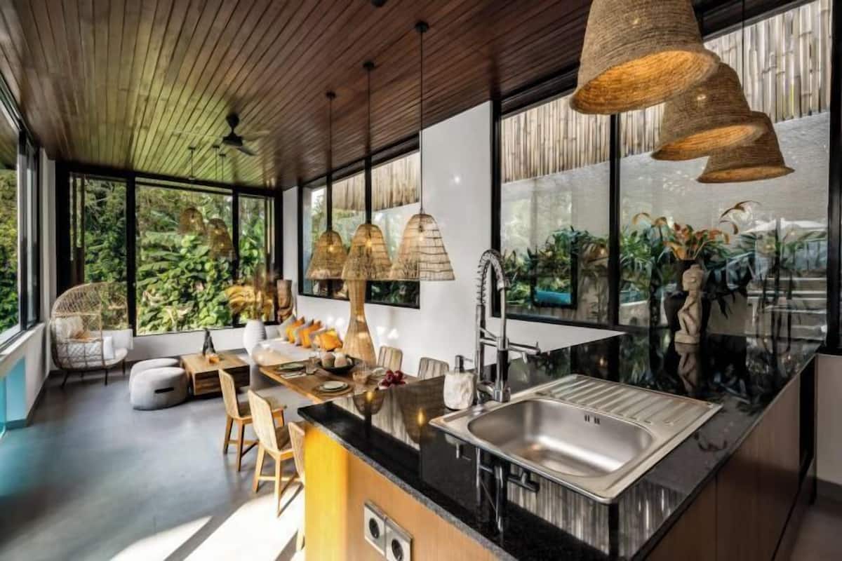 A modern kitchen with a large island, stainless steel sink, and pendant lighting.