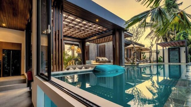 A modern pool area with a clear view of the pool, lounge chairs, and surrounding tropical vegetation.
