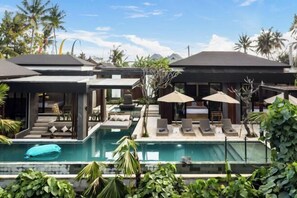 Un complexe hôtelier moderne doté d’une piscine, de chaises longues et de parasols.