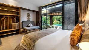 A modern bedroom with a large bed, a seating area, and a wooden wardrobe.