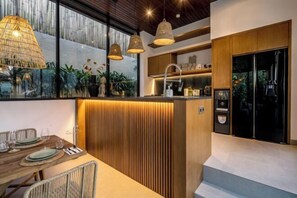 Une cuisine moderne avec un îlot central en bois, des luminaires suspendus et une vue sur l’extérieur.