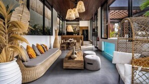 A modern interior with a long dining table, a sofa with cushions, and a wooden coffee table.