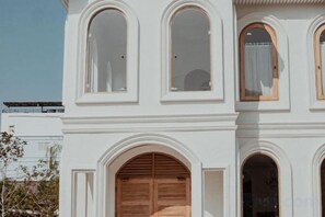 A multi-story building with arched windows and a large wooden door. - Arpo Pool Villa Riverside Bangkok (Bangkok)