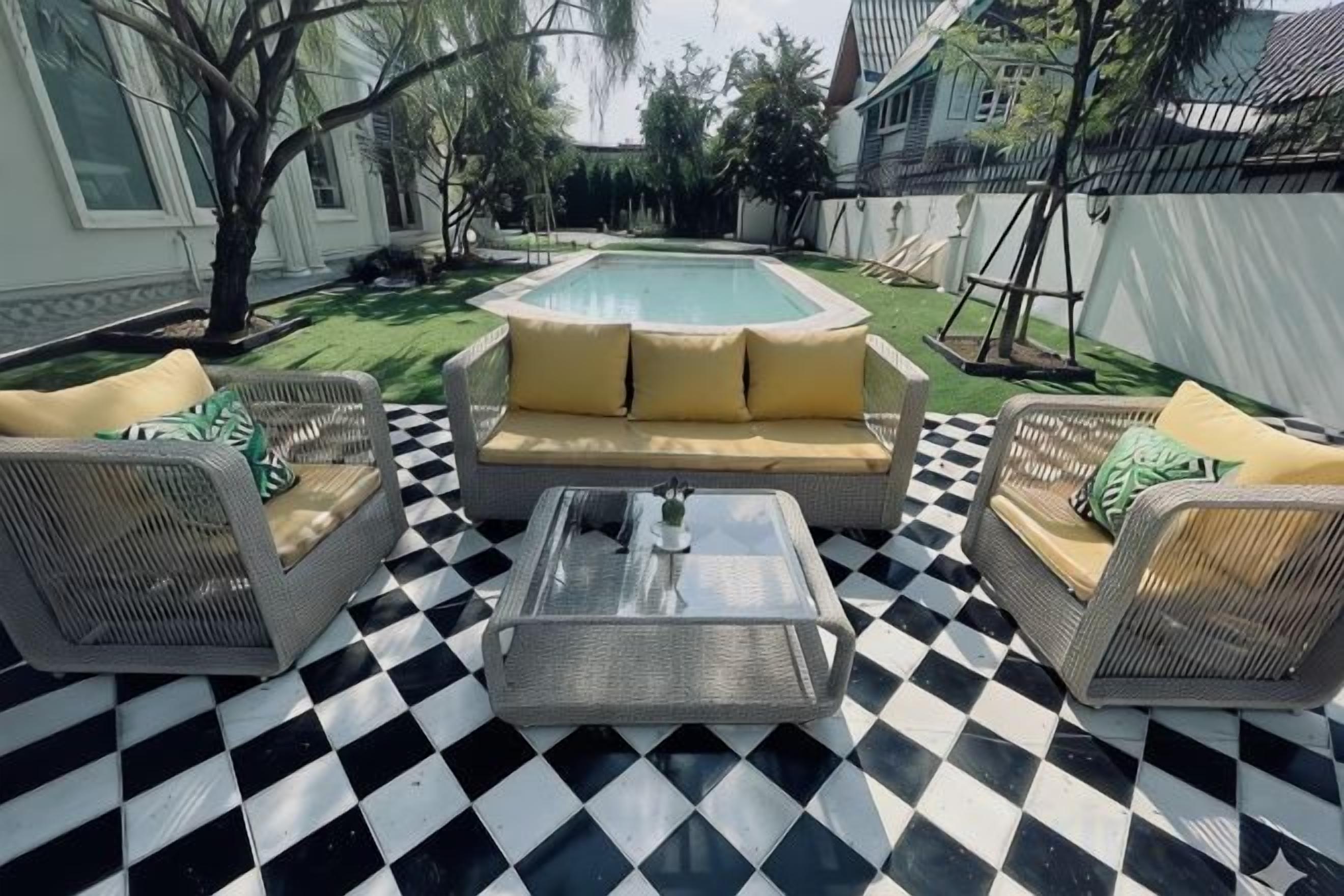 A poolside seating area with a checkered floor, a sofa, and two chairs.