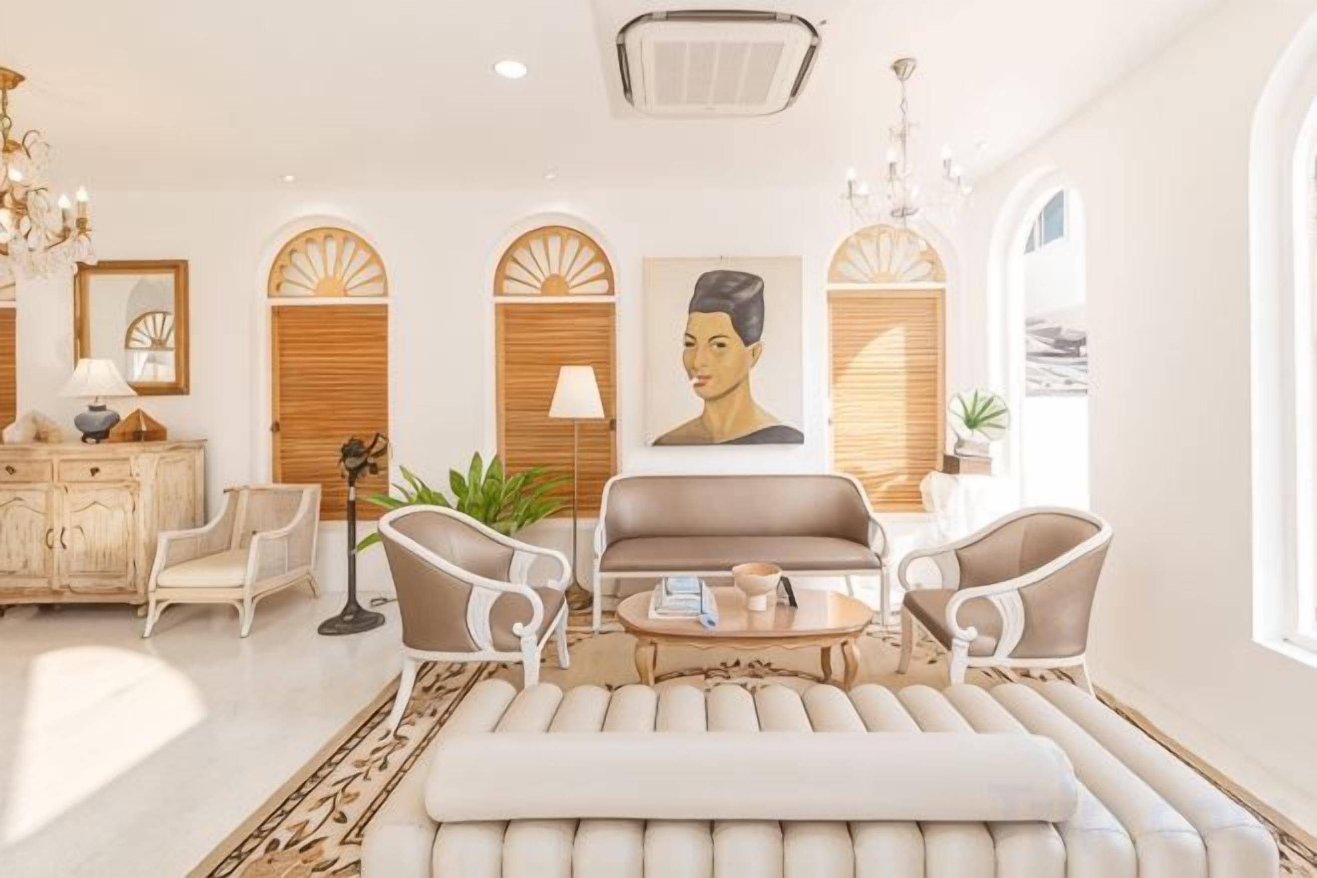 A well-lit living room with a sofa, armchairs, a coffee table, and a chandelier.