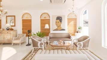 A well-lit living room with a sofa, armchairs, a coffee table, and a chandelier.