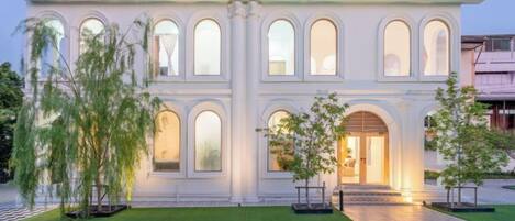 Un edificio grande y blanco con varias ventanas arqueadas y una piscina delantera.