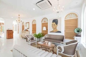 A spacious hotel lobby with a modern design, featuring a central seating area with sofas and armchairs, a chandelier, and a large painting on the wall. - Arpo Pool Villa Riverside Bangkok (Bangkok)
