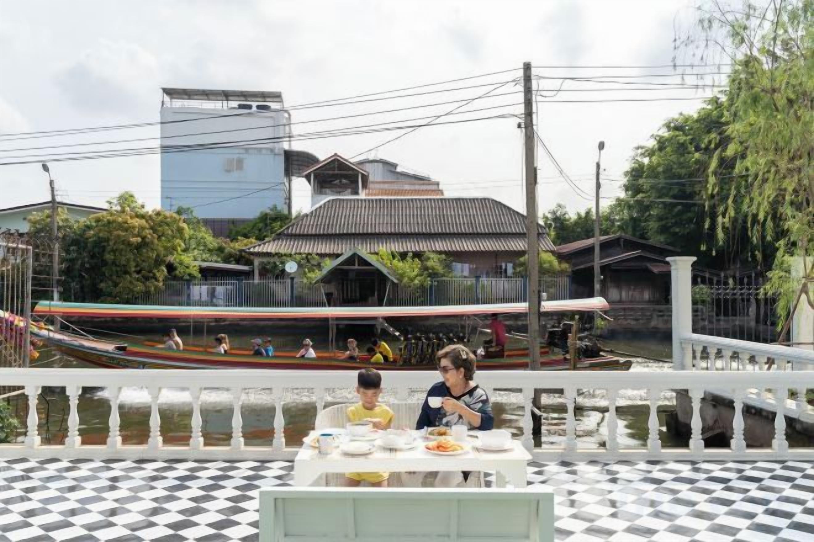 A dining area with a checkered floor, a table with dishes, and a view of a traditional building with a sloped roof.