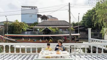 A dining area with a checkered floor, a table with dishes, and a view of a traditional building with a sloped roof.