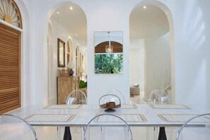 A dining area with a long table, clear chairs, and a central decorative item. - Arpo Pool Villa Riverside Bangkok (Bangkok)