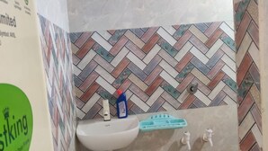 Un bany amb un lavabo blanc, un vàter de mà i una paret revestida amb mosaics de punt de petonsina.