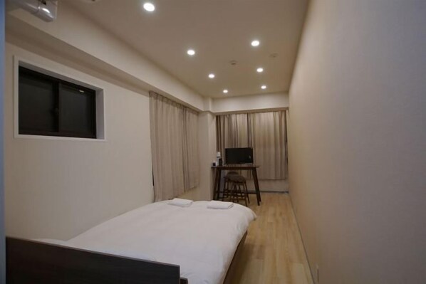 Ein Hotelzimmer mit einem Bett, einem Fernseher auf einem kleinen Tisch und Vorhängen an den Fenstern.