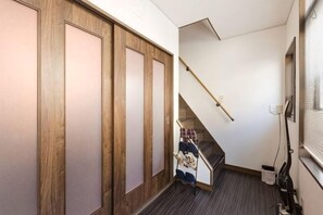 A narrow hallway with wooden doors, a staircase, and a window with blinds. - Tenichikaku (Kyoto)
