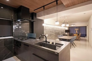 Una cocina moderna con una isla central, horno empotrado y una zona de comedor con mesa y sillas.
