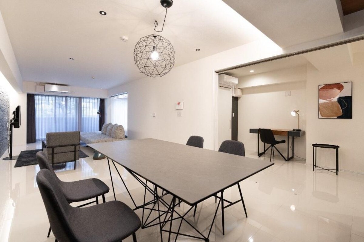 A modern conference room with a large table, chairs, and a unique geometric pendant light.