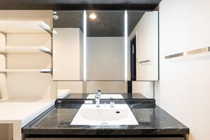A bathroom with a white sink, a mirror above it, and a towel rack to the left. - CREAL premier Akasaka (Minato-ku)