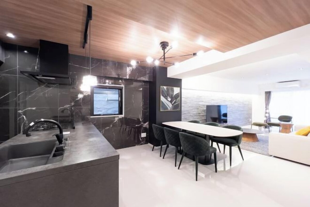 A modern kitchen with a marble backsplash, a built-in stove, and a dining area with a white table and dark chairs.