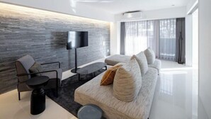 A modern living room with a sofa, armchair, and a flat-screen TV mounted on a textured wall. - CREAL premier Akasaka (Tokyo)