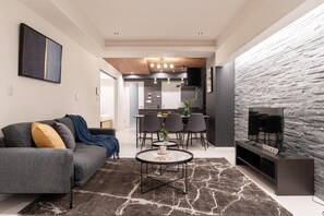 A modern living room with a sofa, coffee table, and a stone accent wall. - CREAL premier Akasaka (Minato-ku)