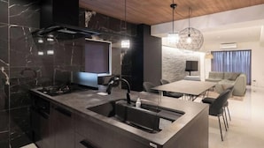 A modern kitchen with a built-in stove, a sink, and a dining area with a table and chairs. - CREAL premier Akasaka (Tokyo)