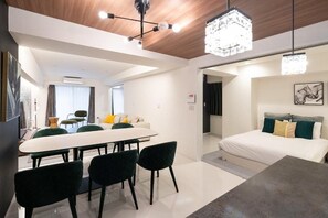 A modern hotel room with a dining area, a bed with a headboard, and a chandelier. - CREAL premier Akasaka (Minato-ku)