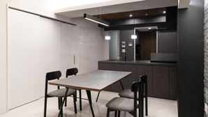 Una cocina moderna con comedor, con una mesa rectangular y sillas, horno empotrado e iluminación colgante.