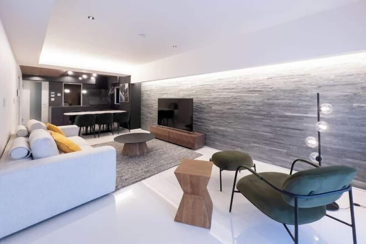 A modern living room with a sofa, a coffee table, a TV, and a stone wall.