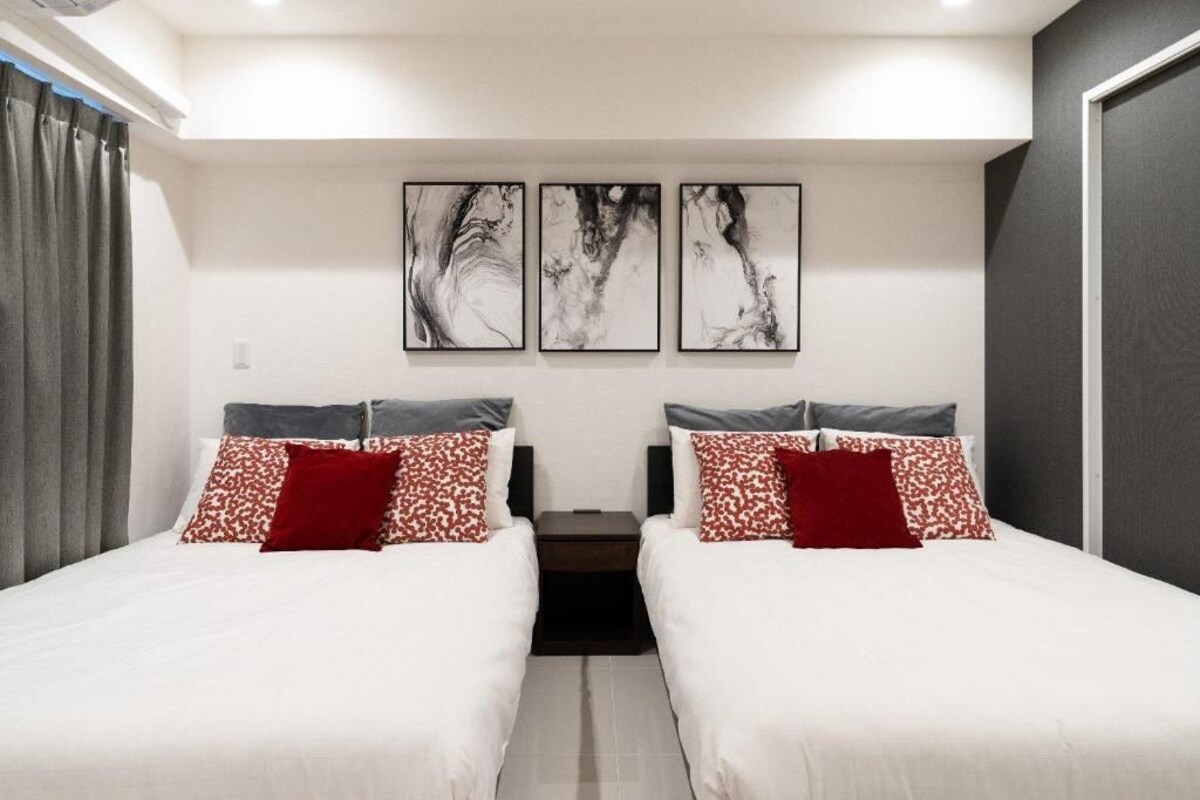 A hotel room with two beds, a nightstand, and abstract wall art.