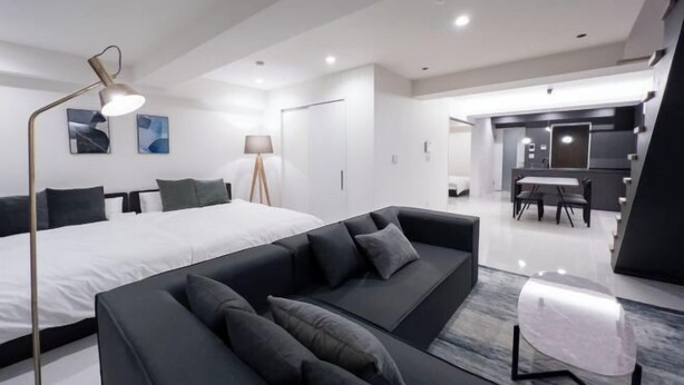 A modern hotel room with a large bed, a black sofa, a desk, and a dining area. - CREAL premier Akasaka (Minato-ku)