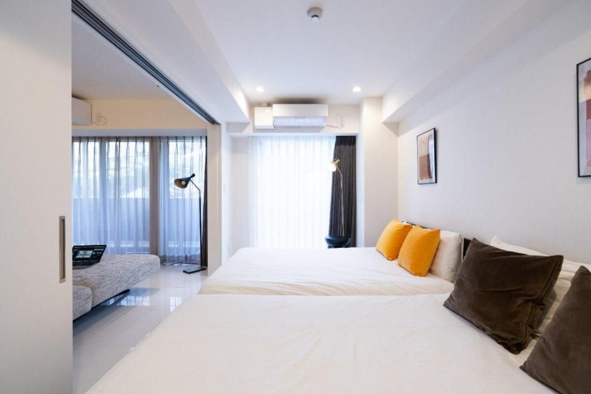 A modern hotel room with a large bed, a sofa, and a desk with a laptop.