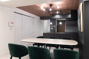 A conference room with a long table and six chairs, a kitchenette in the background, and a ceiling with recessed lighting. - CREAL premier Akasaka (Minato-ku)