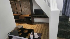 A modern interior with a staircase, a wooden floor, and a table with a black surface. - Hotel My Cang (Tra Vinh)