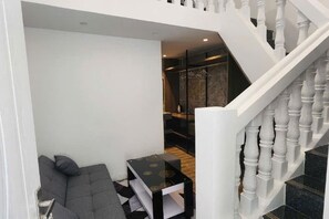 A modern interior with a staircase, a seating area, and a dining table. - Hotel My Cang (Tra Vinh)
