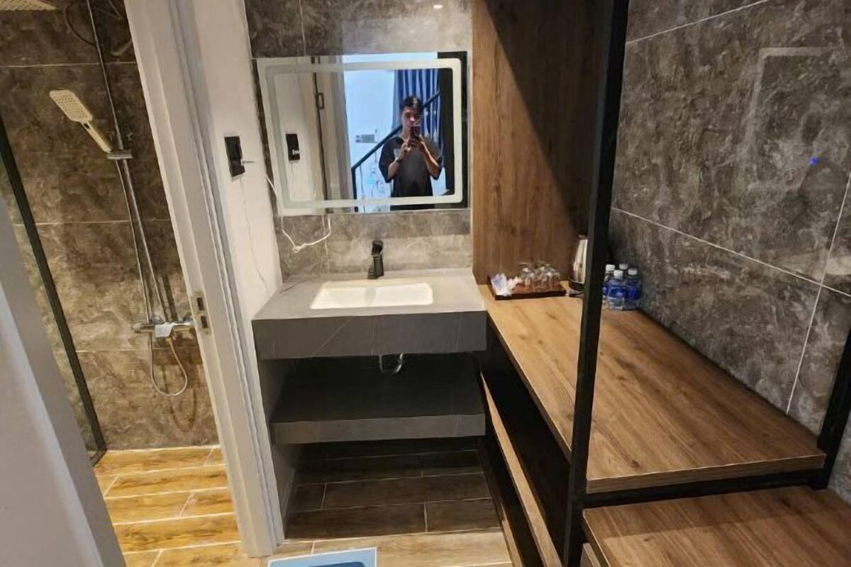 Un baño moderno con un espejo grande, un lavamanos y una zona de ducha.