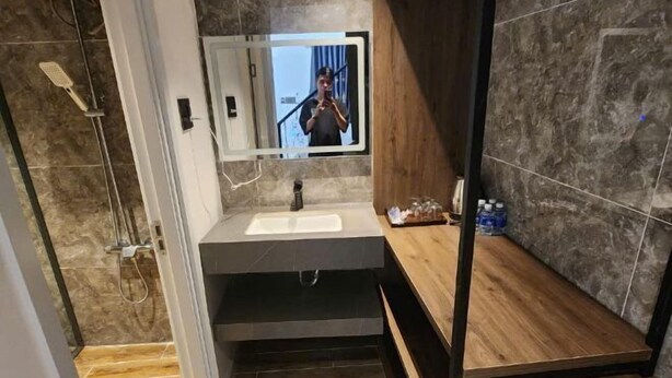 A modern bathroom with a large mirror, a sink, and a shower area. - Hotel My Cang (Tra Vinh)