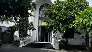 A building with a grand entrance, a staircase leading up to a door, and a large tree in front. - Hotel My Cang (Tra Vinh)